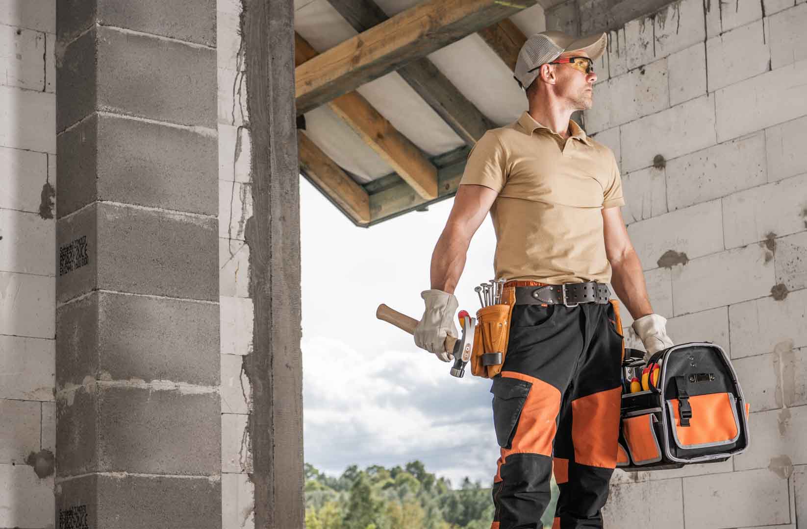 Construction,Contractor,Worker,Standing,And,Holding,A,Tool,Bag,In